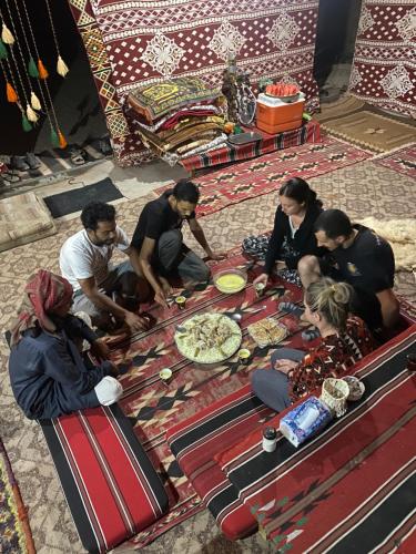 瓦迪拉姆Wadi Rum Desert Base Camp的一群人坐在桌子旁,吃比萨饼