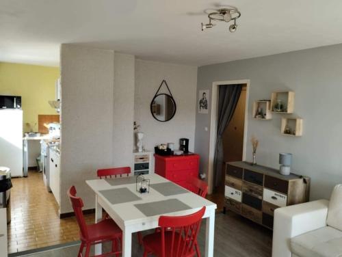 莱鲁斯Appartement les Rousses Bien situé的厨房以及带白色桌子和红色椅子的客厅。