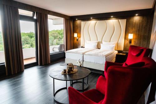 蒂门多弗施特兰德PLAZA Premium Timmendorfer Strand的酒店客房配有一张床、两把椅子和一张桌子
