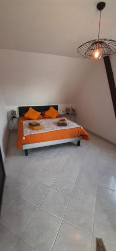 豪森Le grenier de Véro的一间卧室配有一张带橙色棉被的床