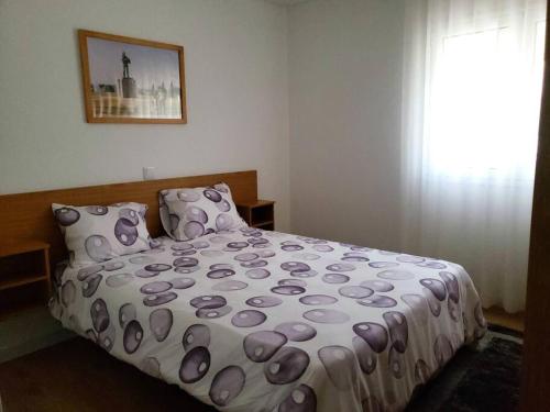 法蒂玛Monte dos Pastorinhos的一间卧室配有一张带紫色棉被的床和窗户。