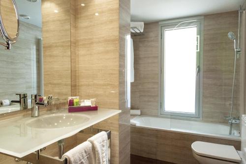 巴塞罗那泽尼特巴塞罗那酒店的一间带水槽和浴缸的浴室以及窗户。