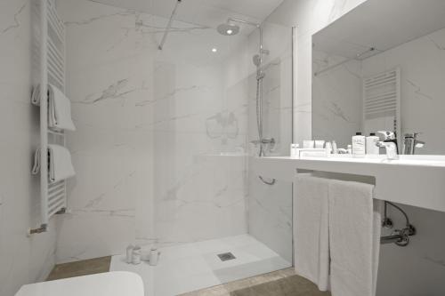 奥维多Hotel Zentral Ramiro I Oviedo的带淋浴和盥洗盆的白色浴室