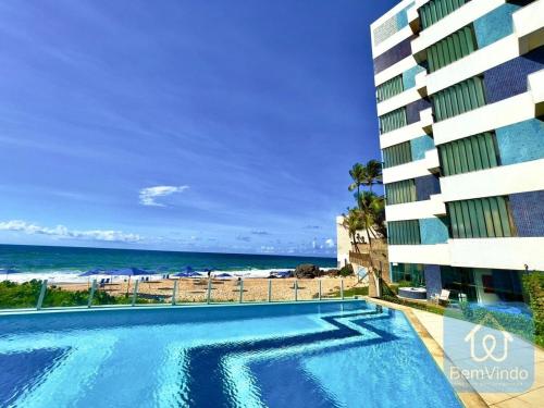 萨尔瓦多Apartamento completo e pé na areia no Rio Vermelho的大楼前的游泳池和海滩
