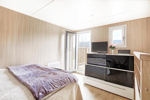 旺特龙POP'S colors - Chalet dans les Vosges的一间卧室配有一张床和一台平面电视