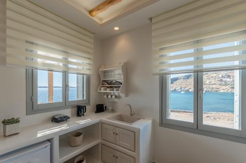 斯希努萨岛Porto Dema Luxury Suites的一间带水槽的浴室和两个窗户