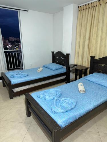 佛罗里达布兰卡Hospedaje Balcones de la Colina的客房设有两张带蓝色床单的床和阳台。