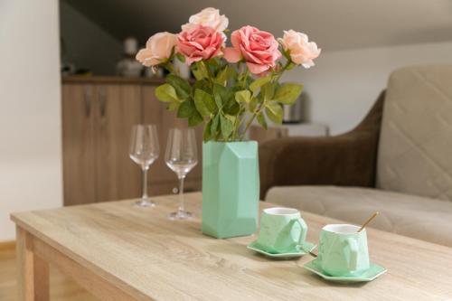 比耶洛波列APARTMAN MIKI BIJELO POLJE的一张桌子,上面有一团粉红色玫瑰花和两杯眼镜