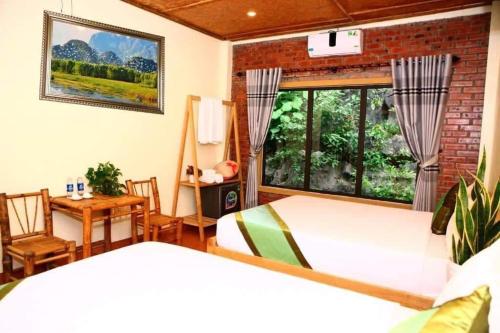 宁平Tam Coc Valley Homestay的一间卧室设有两张床、一张桌子和一个窗口