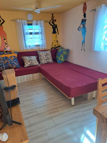 图利亚拉le tamarin的客厅配有紫色沙发和墙上的绘画