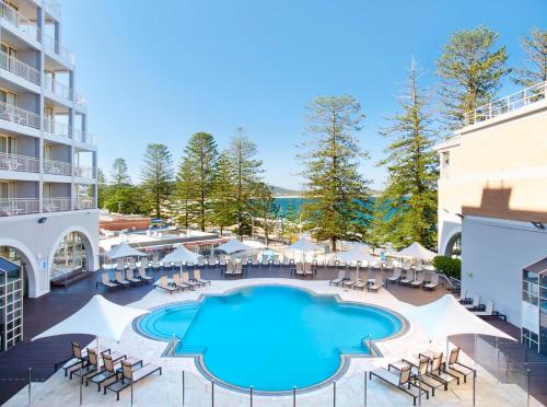 特里格尔Crowne Plaza Terrigal Pacific, an IHG Hotel的一张带桌椅的度假村游泳池的图片