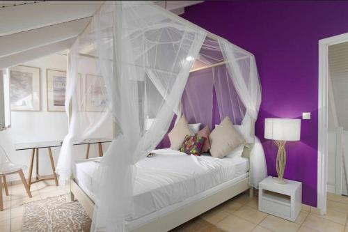 圣吕斯Villa Mango 150 mètres plage à pied的卧室配有白色华盖床和紫色墙壁