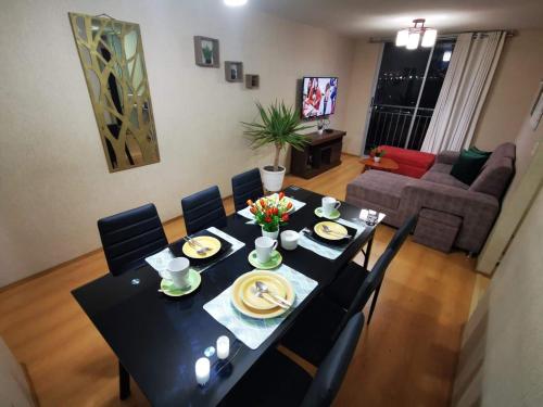 塔克纳Hermoso departamento en condominio的一张黑色餐桌,配有椅子和盘子