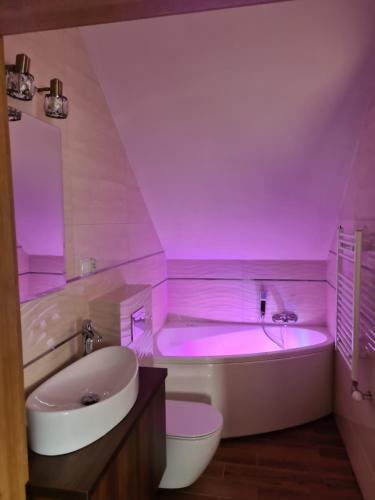 GolczowiceMARMI Noclegi的带浴缸的浴室和粉红色的照明