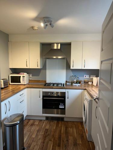 爱丁堡Newbuild - 3 bedrooms, 2 baths,5 mins from airport的厨房配有白色橱柜和炉灶烤箱。