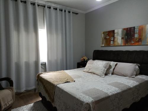 瓜拉廷格塔Casa da Nice的卧室配有带白色窗帘的床和窗户。