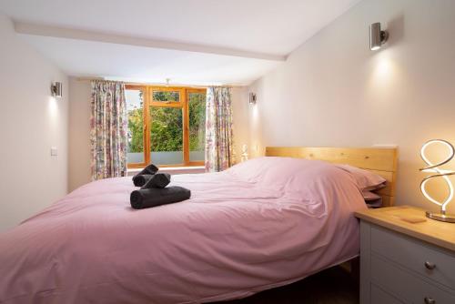 林顿Coachman's Quarters的一间卧室配有粉红色的床,上面有泰迪熊