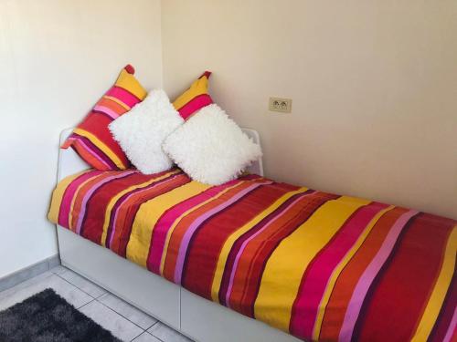 奥斯坦德La vie à Ostende的一张带彩色条纹毯子和枕头的床