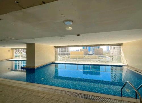 迪拜Serenity Paradise 2BR in Marina的一座大型游泳池,位于一座带大窗户的建筑内