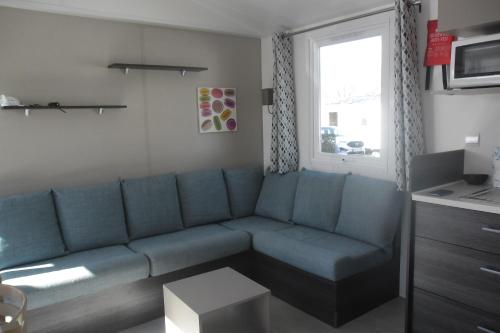 拉康提内勒Mobil home的客厅设有蓝色的沙发和窗户。