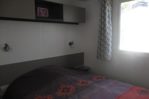 拉康提内勒Mobil home的一间卧室设有一张床和一个窗口
