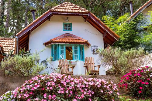 蒙特韦尔迪Pousada Vila Suiça - Monte Verde的白色的小房子,有蓝色的窗户和鲜花