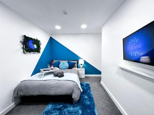 Enfield LockCosy Contemporary Apartment - Brimsdown, Enfield的一间卧室设有蓝色墙和一台大电视