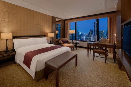 曼谷曼谷苏坤喜来登豪华精选大酒店的一间卧室配有一张床、一张书桌和一个大窗户