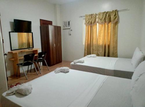 BanbanRedDoorz @ 4ks Pension House Bogo City Cebu的客房设有两张床、一张桌子和一台电视。