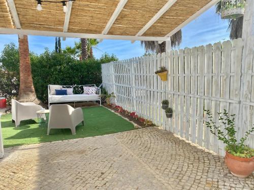 法鲁Casa Pedra Rosa - VINHAS de NEXE的庭院设有白色的围栏和桌椅。