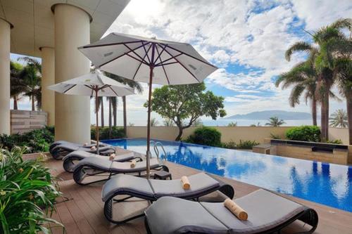 芽庄Central Nha Trang Apartment的游泳池旁一排带遮阳伞的躺椅