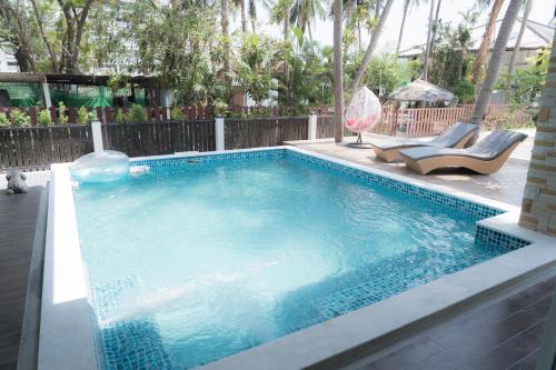 佛丕Nirvana Hua Hin Pool Villa的一个带2把躺椅的游泳池和一个游泳池