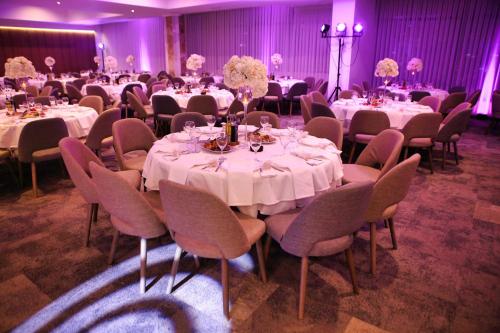 什蒂普Oaza Hotel的宴会厅配有桌椅和白色的桌布