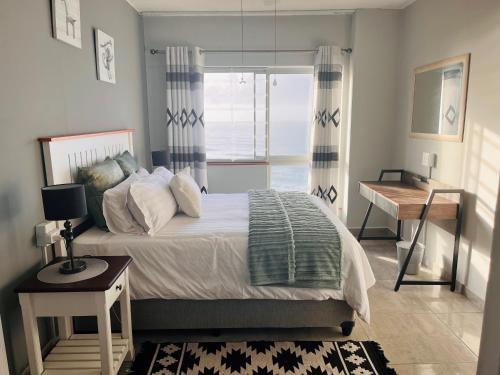 马盖特Santana 804 Beachfront Apartment with spectacular sea views的一间卧室配有一张床、一张书桌和一个窗户。