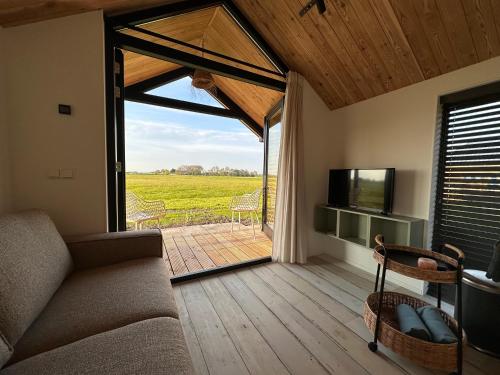 NoordenGastenverblijf De Natureluur的带沙发和滑动玻璃门的客厅