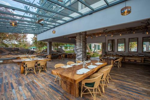 坎哈The Riverwood Forest Retreat - Kanha的餐厅铺有木地板,配有木桌和椅子