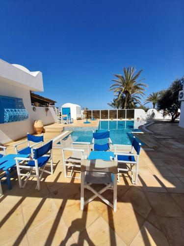 Al ḨaddādahDar Lagune Djerba的一个带蓝白色椅子和桌子的游泳池