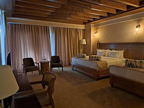 撒马尔罕Kosh Havuz boutique hotel的酒店客房配有一张床、一张沙发和椅子。