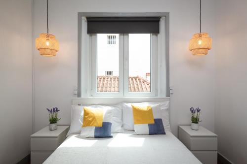 卡尔达斯达·赖尼亚Minimalist Apartment In Caldas的一间卧室配有白色的床和黄色及蓝色枕头