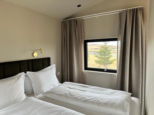 塞尔福斯Urriðafoss Waterfall Lodges的一间卧室配有一张带白色床单的床和一扇窗户。