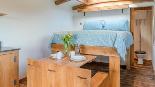 利德尼Betty Shepherd's Hut的一间卧室配有一张床和一张鲜花桌子