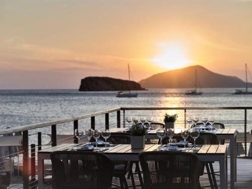 苏尼翁爱琴海岸酒店的日落时分带酒杯和海洋的桌子