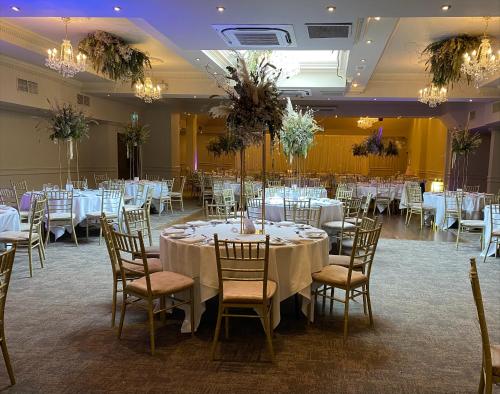 尼纳Abbey Court的宴会厅配有白色的桌椅和吊灯