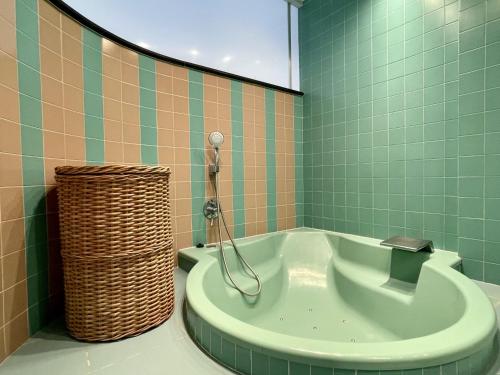 埃斯塔蒂特La Pineda I 1 3-6的浴室铺有绿色瓷砖,配有浴缸。
