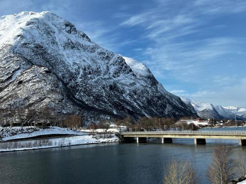 翁达尔斯内斯Frichs Ekspress Åndalsnes的一座有雪覆盖的山的河上的桥梁