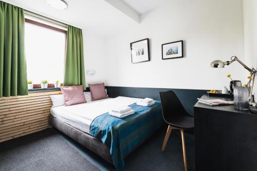 费尔巴赫City Hotel Fellbach 24H CHECK-IN的一间卧室配有一张床、一张书桌和一个窗户。