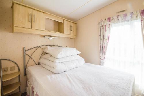 大雅茅斯Great 6 Berth Caravan For Hire At Cherry Tree Holiday Park In Norfolk Ref 70801c的一间卧室配有一张带白色床单的床和一扇窗户。