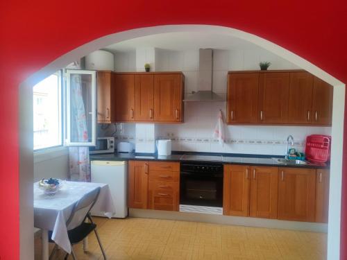 佩德罗佐Apartamentos turísticos Lemos的厨房设有木制橱柜和红色拱门。