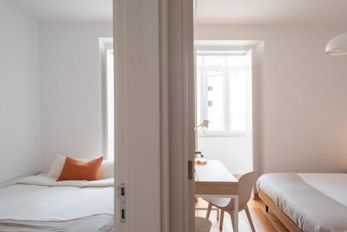 里斯本Amaro II - Sleek 2 bedroom apartment in Alcantara的一间卧室设有两张床、一张桌子和一个窗口。