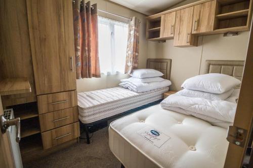 萨克斯曼德姆4 Berth Caravan With Decking And Wifi At Carlton Meres In Suffolk Ref 60010k的小房间设有两张床和窗户